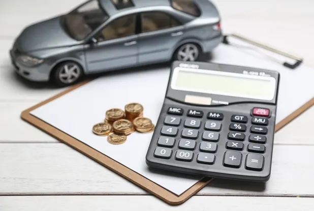 Toy car with a calculator and coins on a clipboard