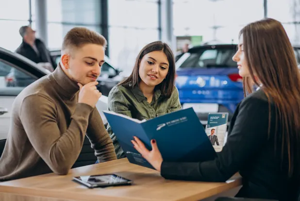 Couple discussing auto loan options with a salesperson at a dealership