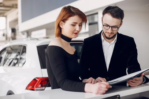 Couple reviewing auto loan paperwork at a car dealership