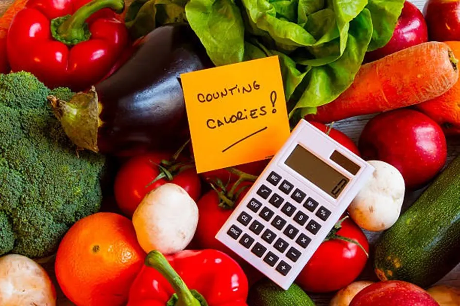 Colourful vegetables arranged around a calculator with a counting calories note