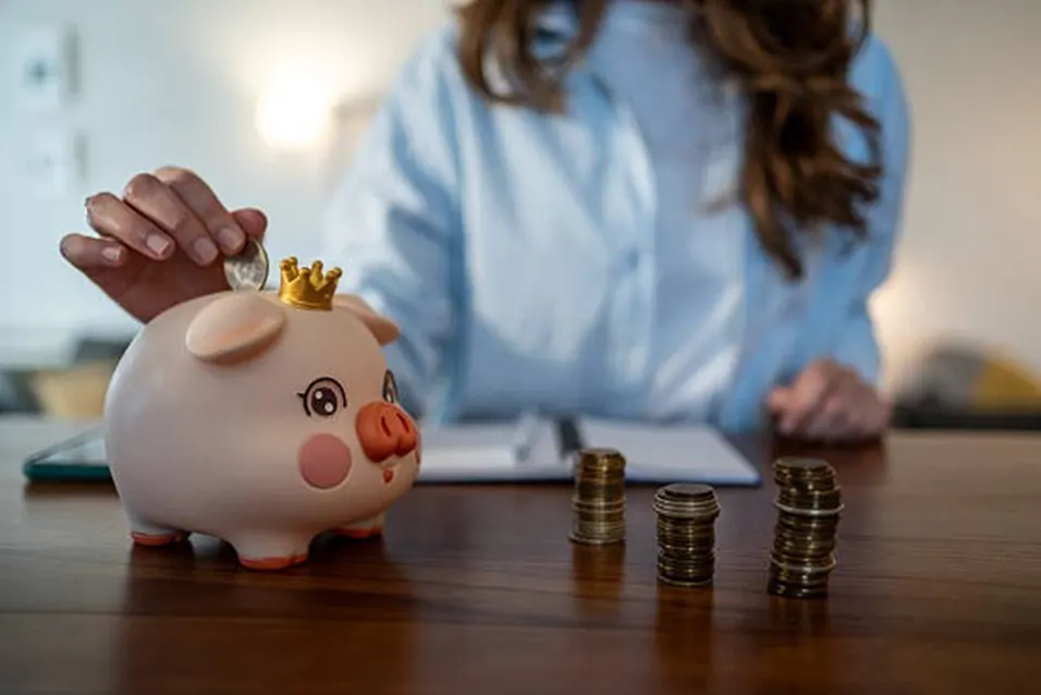 Woman saving coins in piggy bank