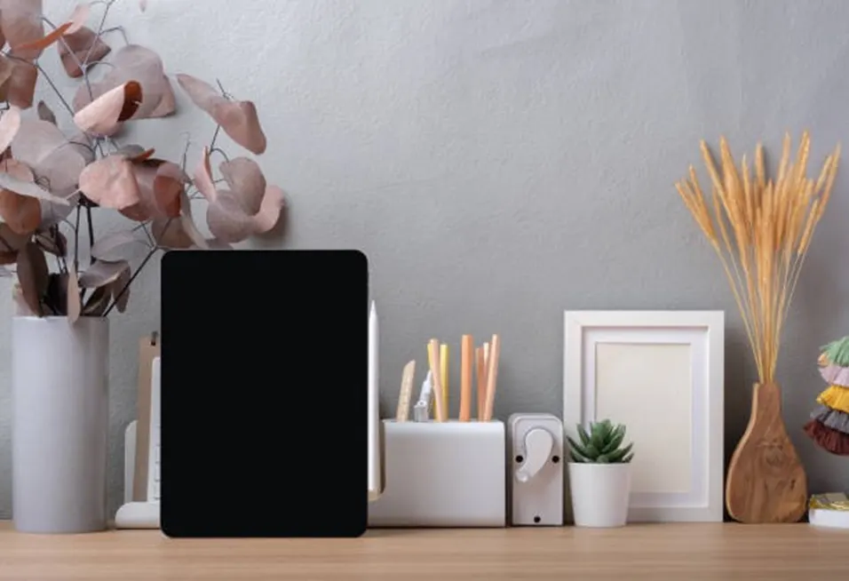 Minimalist desk setup with a black tablet, pencil holder, succulents, photo frame and dried flowers on a wooden shelf