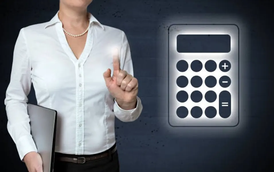 Businesswoman in white shirt touching a glowing digital calculator icon on a dark wall
