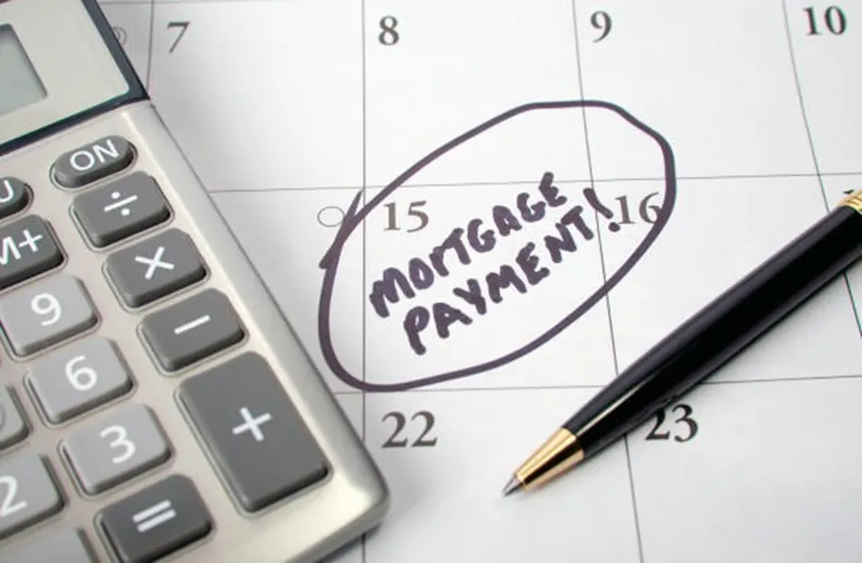 Calculator beside a calendar with Mortgage Payment circled on the 15th and a black pen
