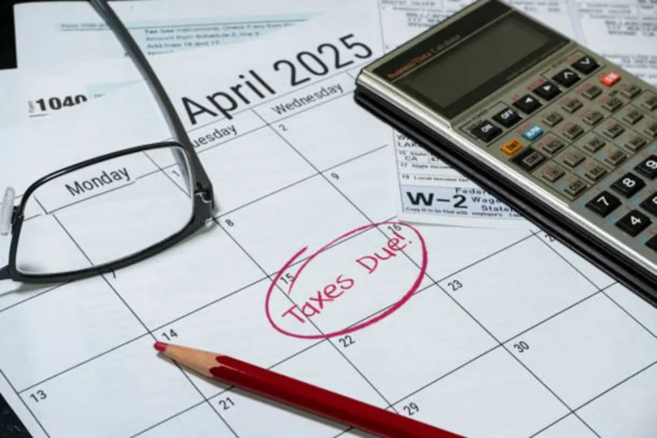 April 2025 calendar with Taxes Due circled in red, alongside glasses, a red pencil, tax forms and a calculator