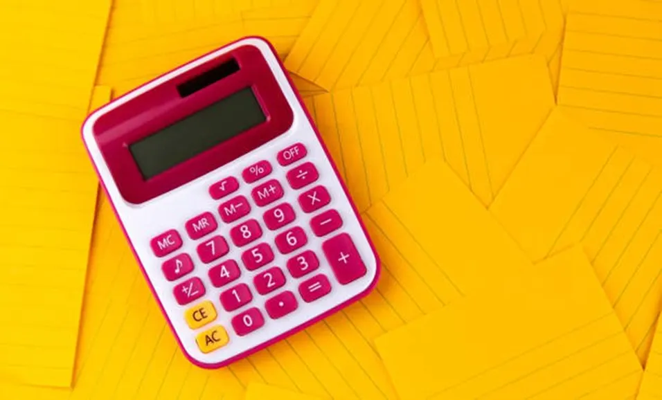 Pink and white calculator placed on a yellow patterned surface