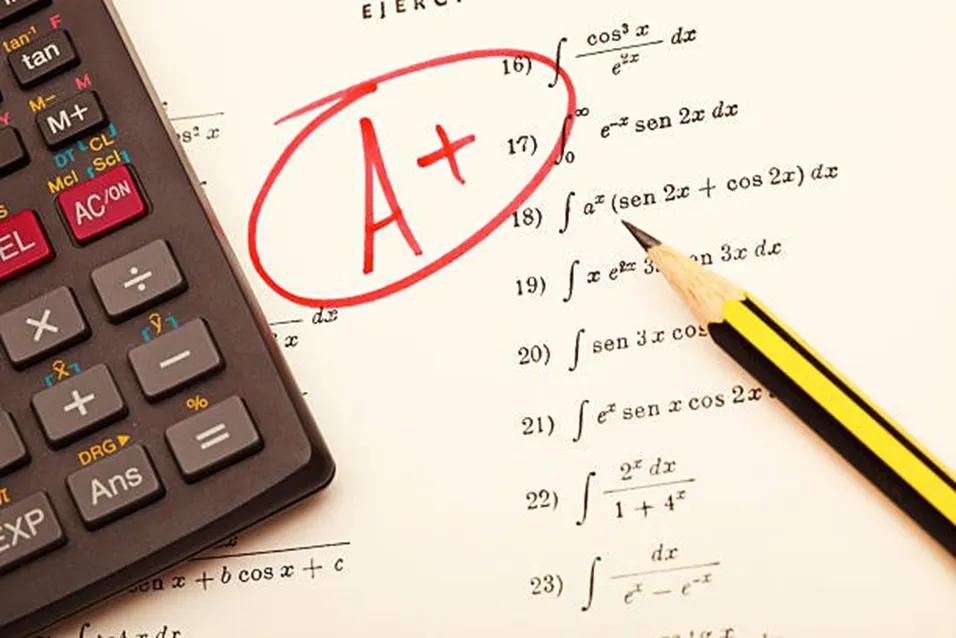 A+ grade circled in red on a maths exam paper beside a scientific calculator and pencil