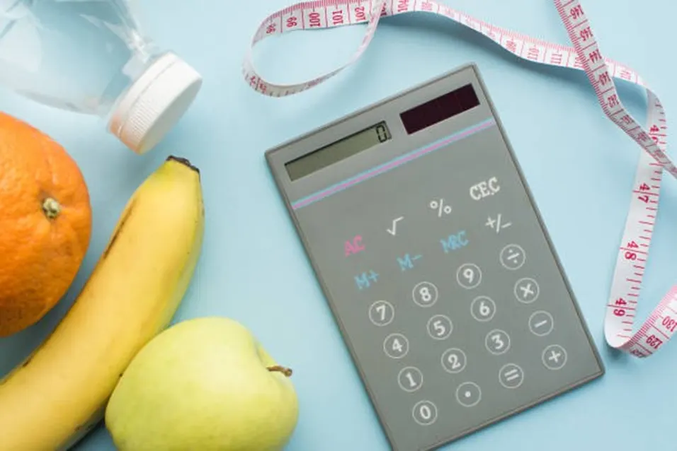 Calculator with fruits and tape measure for ideal weight