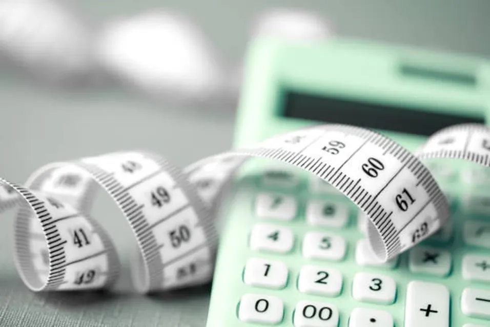 Tape measure curled around green calculator