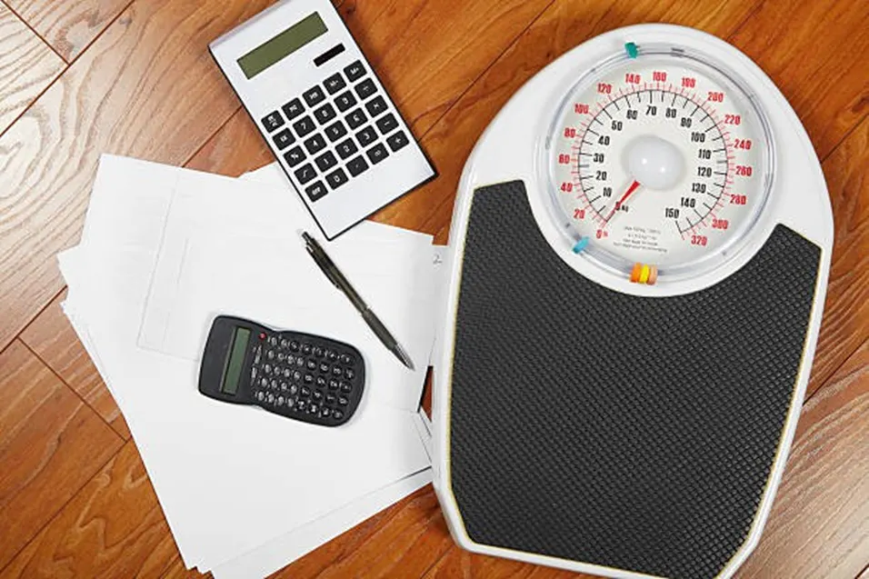 Calculator and weight scale on wooden floor