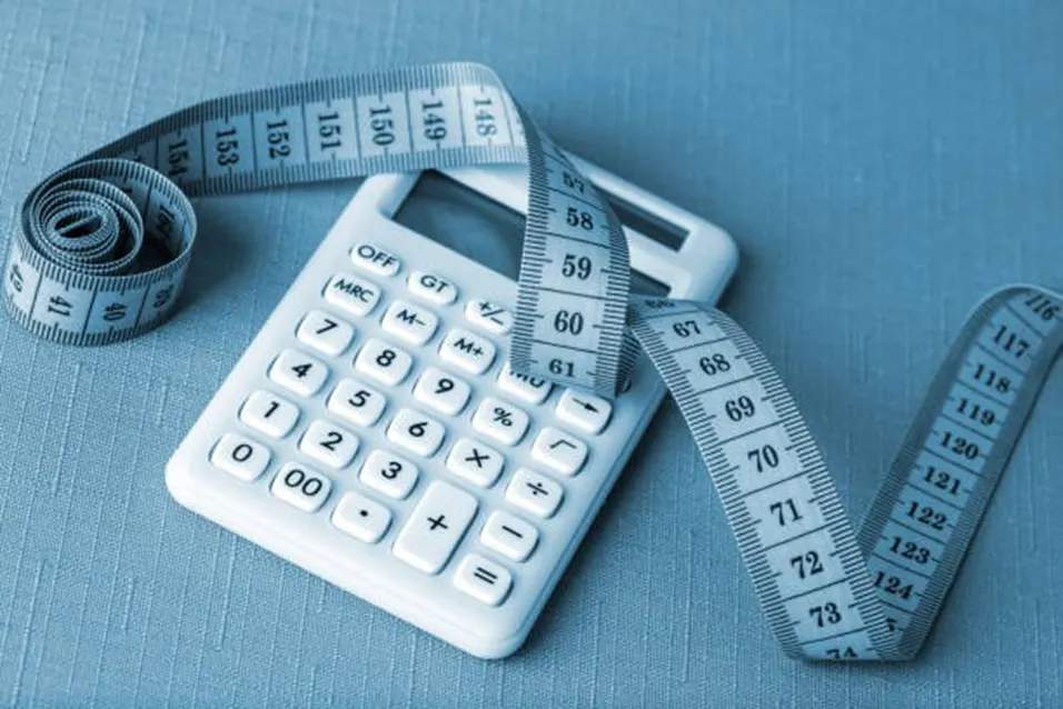 White calculator with tape measure on blue background