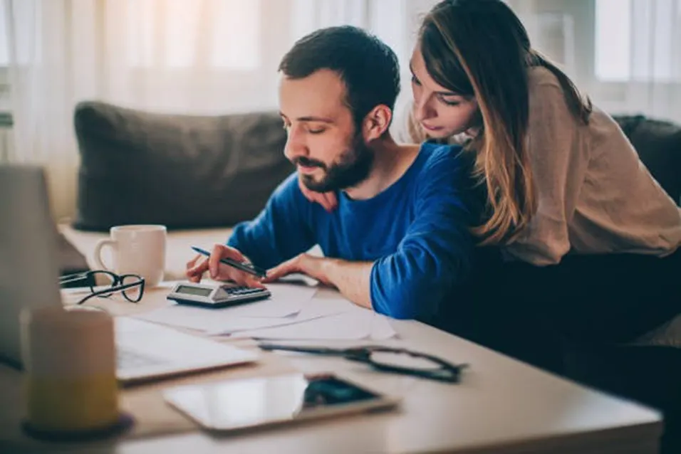 Couple reviewing investment finances together at a table with a calculator and paperwork