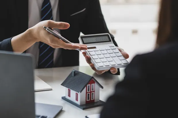 Agent showing calculator to client with house model