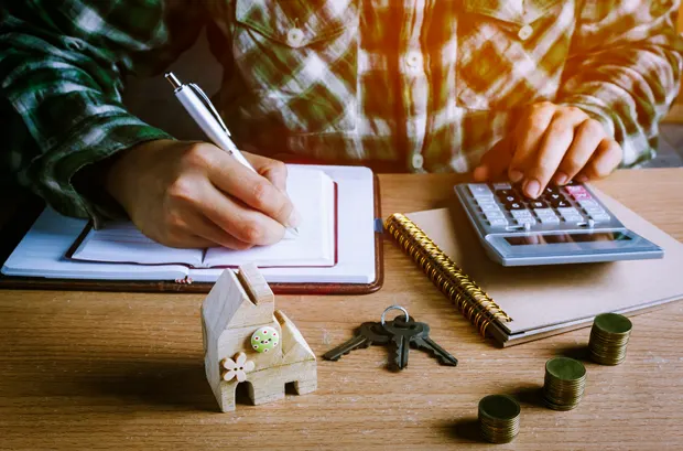 Person writing mortgage notes with house model