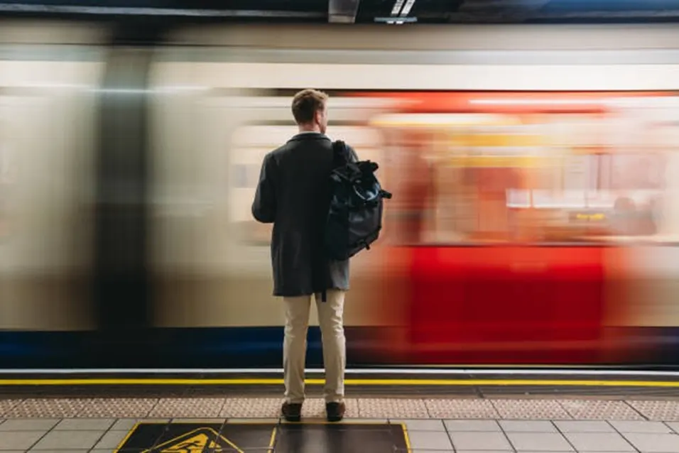 Person standing at subway platform watching a fast-moving train