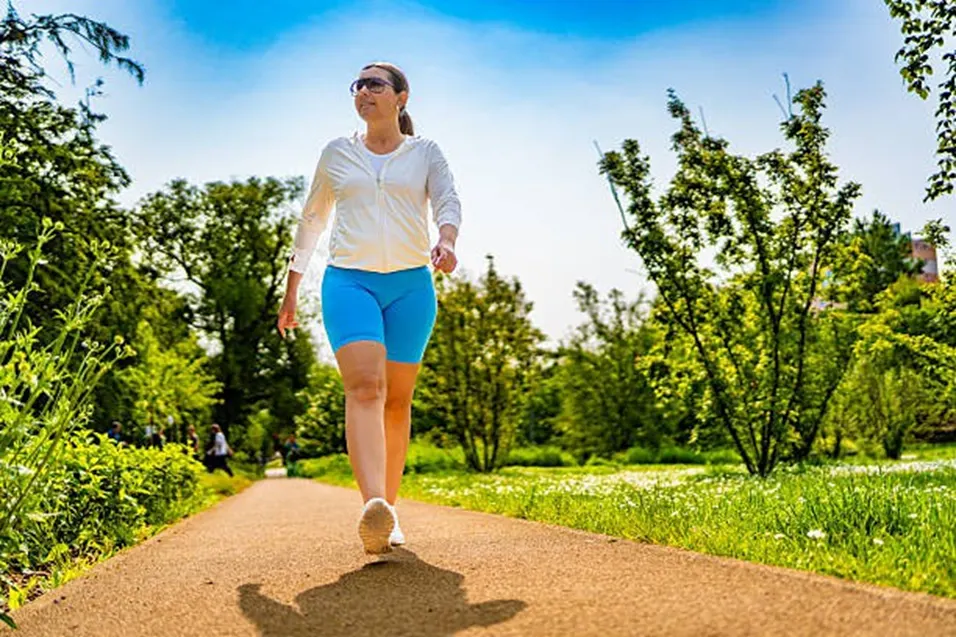 Woman walking briskly along a sunny park path