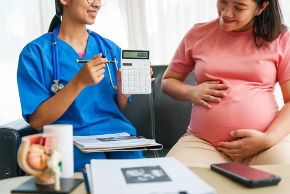 Nurse showing a calculator to a pregnant woman during a consultation