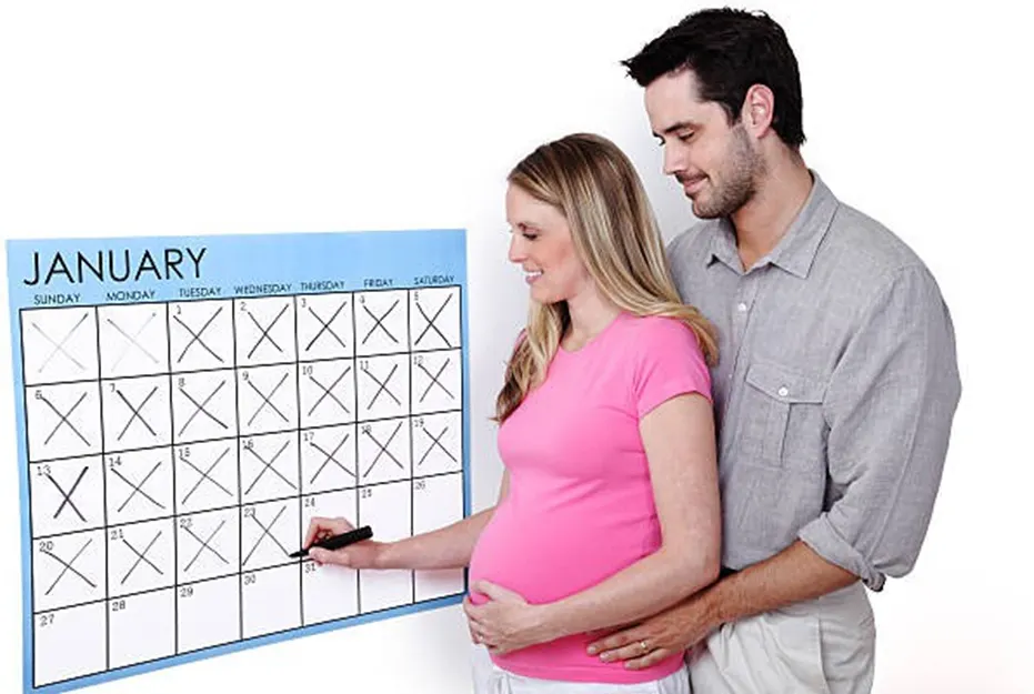 Pregnant couple marking off days on a January calendar together