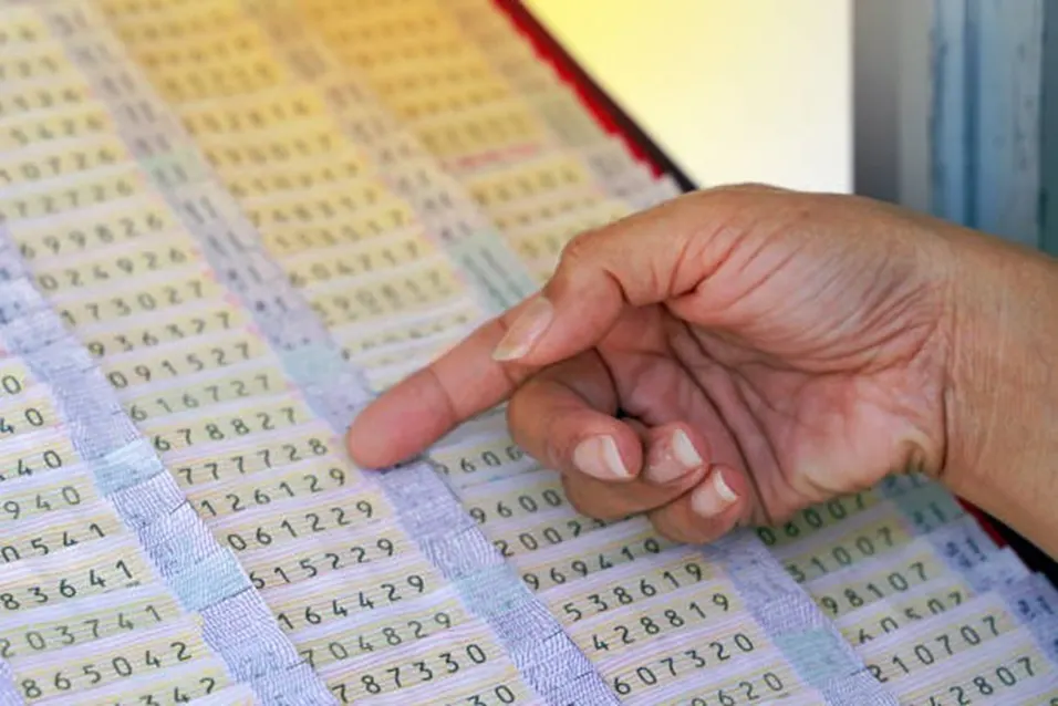 Hand pointing to a row of random number sequences printed on a lottery or statistics table