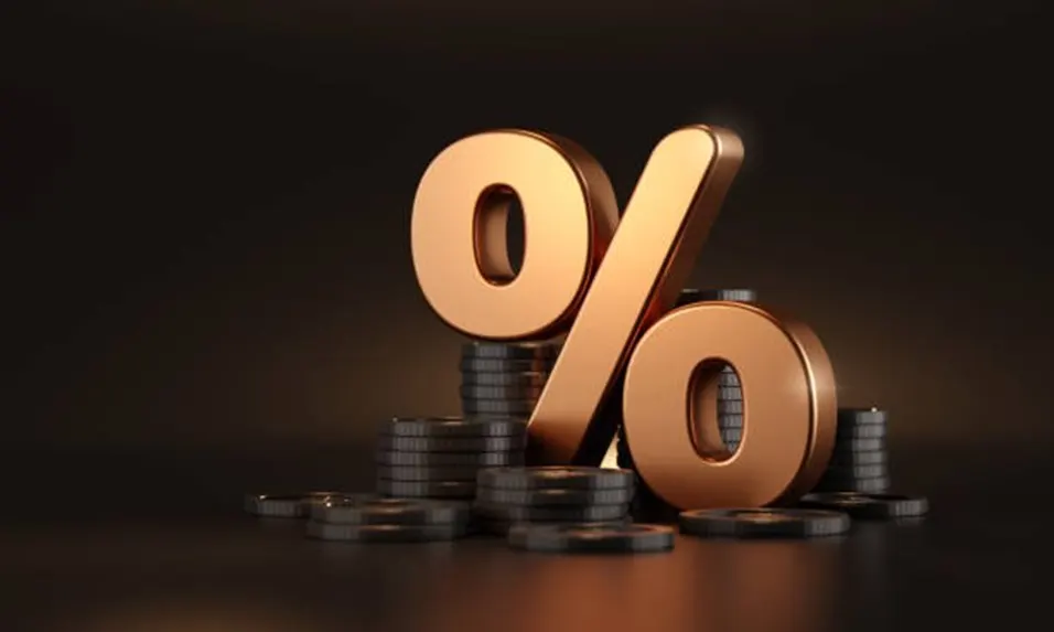 Large golden percent sign surrounded by stacks of coins on a dark background