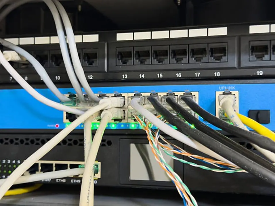 Multiple ethernet cables plugged into a blue network switch with green indicator lights