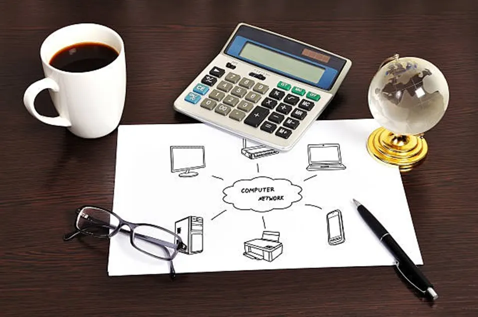 Desk with a computer network diagram, calculator, coffee, glasses and globe