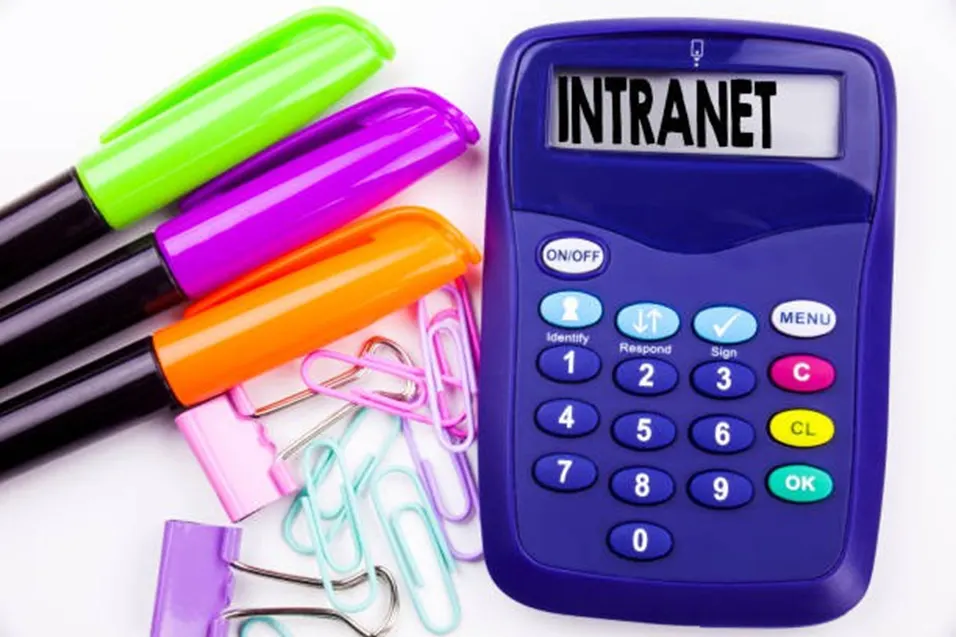 Blue calculator displaying INTRANET beside colourful markers and paper clips on a white surface