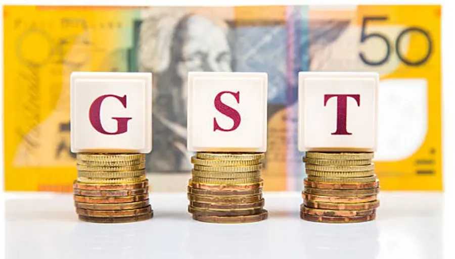 GST letter blocks stacked on coins in front of an Australian 50 dollar banknote