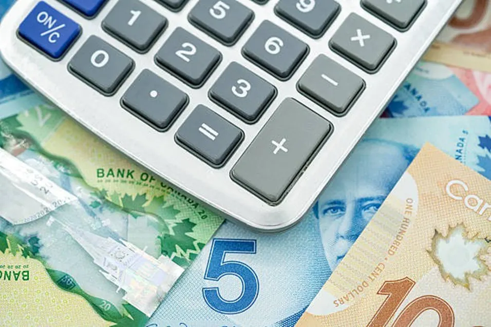 Calculator resting on a spread of Canadian dollar banknotes including five and ten dollar bills