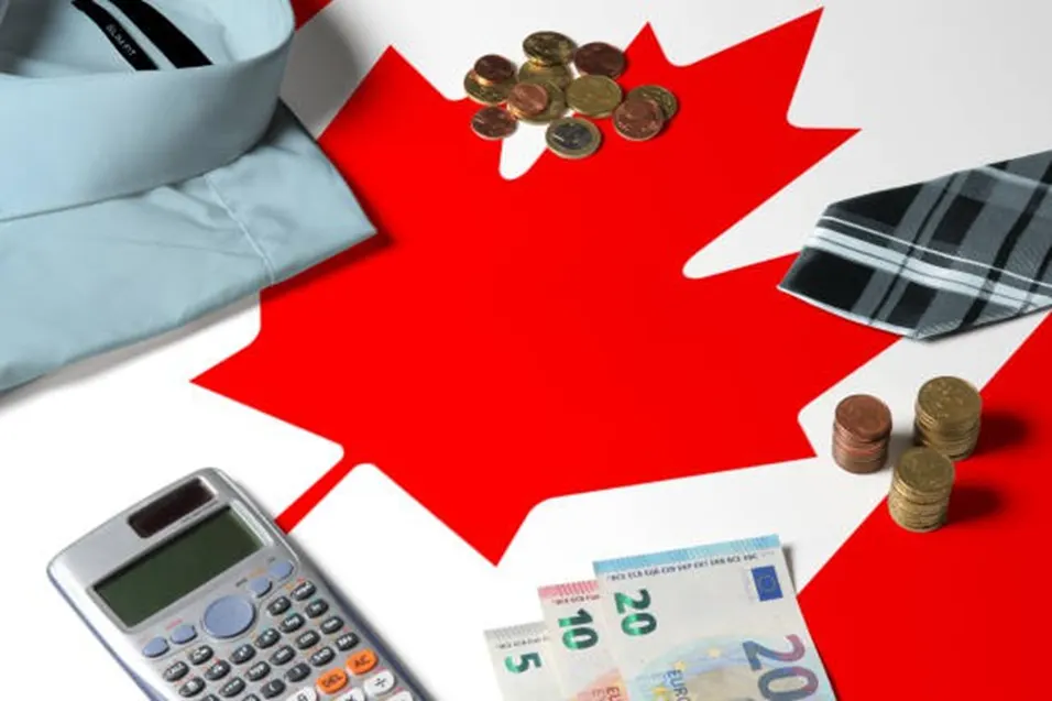 Canadian flag with a calculator, euro banknotes, coins, a shirt, and a tie arranged around the maple leaf