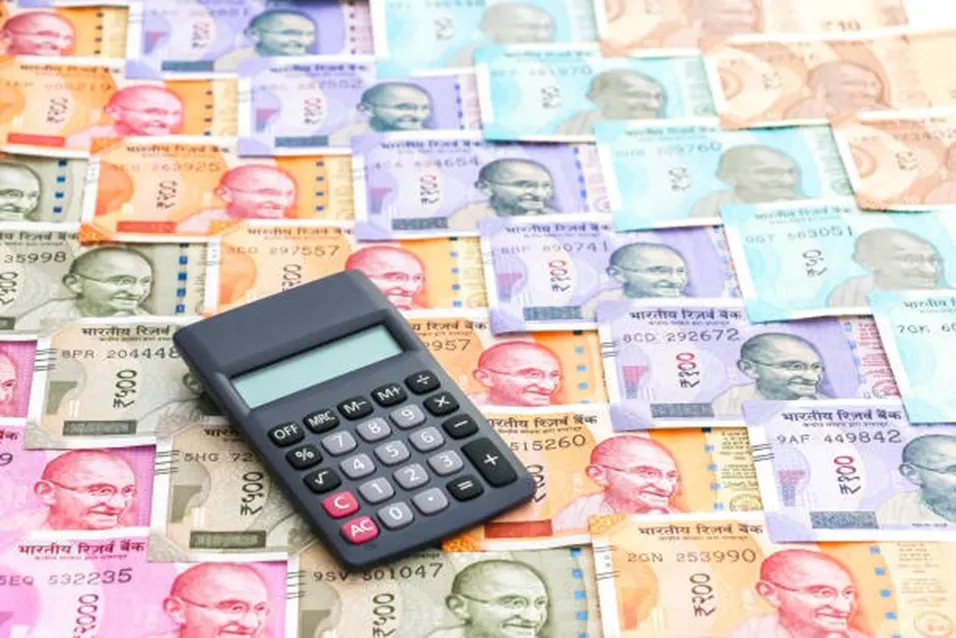 Black calculator placed on top of a spread of colourful Indian rupee banknotes of various denominations
